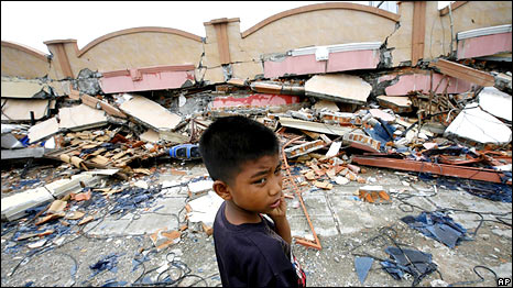 A boy stands near a building flattened by an earthquake in Padang, West Sumatra, Indonesia, Thursday, Oct. 1, 2009