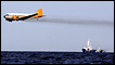 A dispersant plane passes over an oil skimmer as it cleans oil from a leaking pipeline at the Deepwater Horizon oil rig in the Gulf of Mexico near the coast of Louisiana, 27 April 2010
