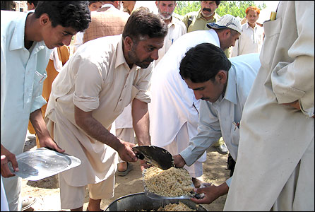 Internally displaced people receive food in a Pakistan refugee camp
