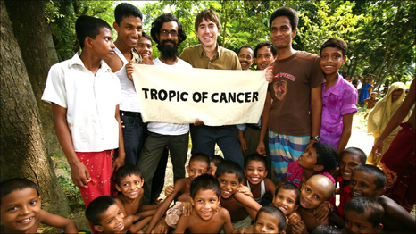 TROPIC OF CANCER WITH SIMON REEVE - Simon in Bangladesh with his guide Tanjil and a crowd of locals who gathered when the camera was produced. Photograph © Simon Reeve. 