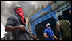 A private security guard stands outside a burning store in downtown Port-au-Prince. January 19, 2010. REUTERS/Carlos Barria  