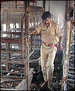 Indian police officer inside a gutted train carriage