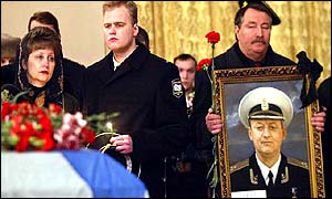 Captain Lyachin's widow and son and an unidentified man holding his portrait