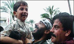 Palestinian militant holds his son in celebration as he and fellow militants arrive in Gaza