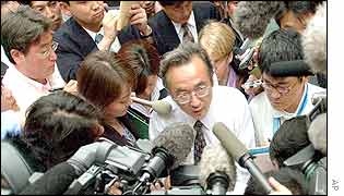 Japan delegate Masayuki Komatsu is mobbed by the media  