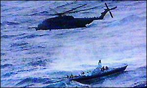 A helicopter attempts to winch rescuers on to the yacht