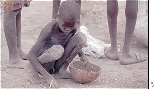 A boy picks up grains of maize spilled from a burst sack 