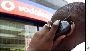 Man using mobile phone outside Vodafone shop