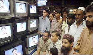 Shopkepers and passers-by watch General Musharraf's speech 