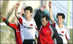 Chinese defender Sun Jihai (L) and midfielder Li Xiaopeng (R) train with an assistant coach 