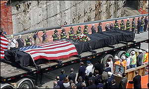 The last steel beam that was standing from one of the World Trade Center towers is driven from ground zero past a group of dignitaries 