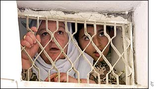 Women watch the incursion from a barred window