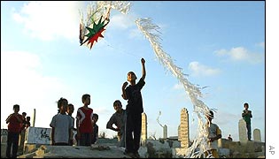 Palestinian children fly a kite in a Gaza cemetery 