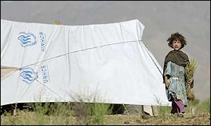 Afghan refugee child stands by a tent