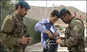 Afghan policemen check a journalist 