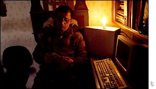 Shop worker reading by candlelight during a power cut in New Delhi, India