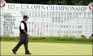Tiger Woods walks in front of the leaderboard at Bethpage Park
