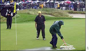 A worker clears standing water from the 18th green at Bethpage