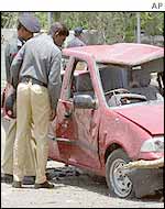 Policemen inspect car damaged in the consulate bombing