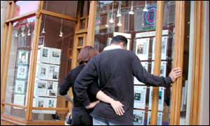 Potential house buyers look in an estate agent window