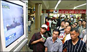 South Koreans watch news reports of the sea battle
