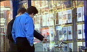 Potential buyers looking in estate agent's window