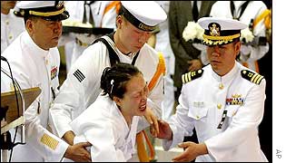 A widow of a South Korean sailor is helped by sailors as she grieves at his funeral