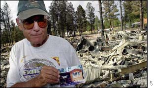 Don Ausburn holds a photograph of his house in Overgaard, next to its remains