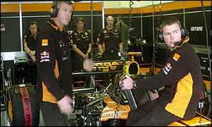 Arrows mechanics sit idly in the team's garage during Friday's practice session