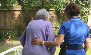 An elderly woman is helped by a carer