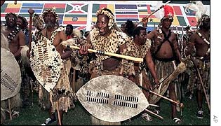 Zulu warriors dance in front of flags representing the nations of Africa