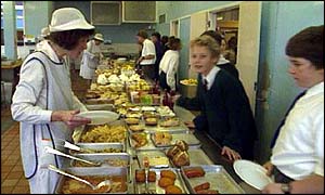 A dinner lady serves children food at a school canteen