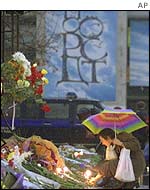 A woman leaves flowers at a memorial for the victims of the theatre siege