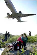 Taiwanese mother holds her son's ears as they  watch a plane land at Taipei domestic airport (AP)