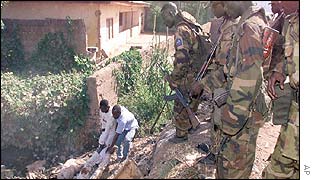 Soldiers watch as a dead body is retrieved in Kaduna