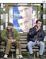 People sitting by Montenegrin election poster