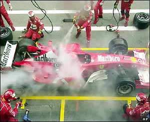The fire is put out by the Ferrari mechanics as Schumacher sits calmly in the driving seat