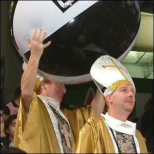 Two spectators holding a huge beach ball are dressed up as cardinals