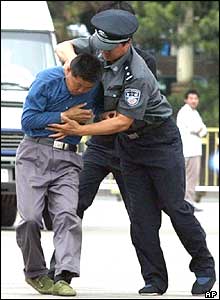A Chinese policeman grabs a protester in Beijing's Tiananmen Square,  June 4, 2004  