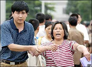 A Chinese woman yells and points to an injury on her arm as a plain clothed policeman detains her in Beijing's Tiananmen Square,  June 4, 2004  