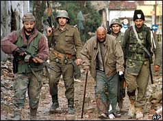 Yugoslav soldiers (background) and Serbian volunteers escorting a Croat civilian 