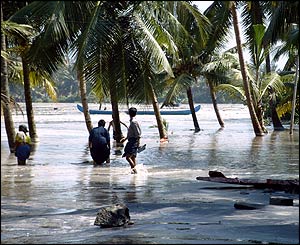 Survivors wade through water near beach in Kerala, India