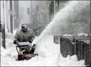 A Boston resident clears snow from the pavement in front of his house