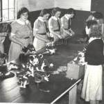 Schoolgirls from Chipping Sodbury Grammar School, at the Food Office, in Sodbury Rural District Council in Lilliput Court, during 1939.  Here they are assembling gas masks.  They were told to spend some part of their summer term in the school year with this task.  From left to right, unknown, Pearl Blakeney (now deceased), Nora Elsa (now deceased), Barbera Woodman, Elsie Broom, not known, Iris Wathern, not known. Moira was in a different group to these girls, so does not appear in this picture.