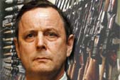 Image of General John de Chastelain, against a montage of weapons