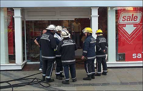 Firefighters cluster around shop door