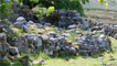 The old ruined farm settlement just before a steep, grassy hillside.