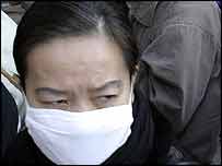 Mulher mascarada em estação de trem em Beijing