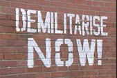 Image of graffiti stating "demilitarise now"