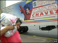 Venezuelana passa diante de cartaz com propaganda do governo